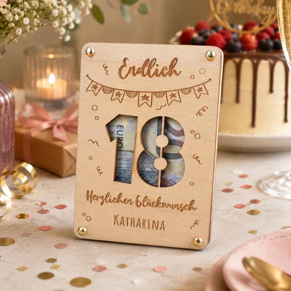 Geldgeschenk Verpackung 18. Geburtstag (aus Holz, personalisiert). Zu sehen auf dekoriertem Geburtstagstisch (abgeschnitten zu sehen: Schoki-Früchte-Torte, Kerze, Blumen, ...)